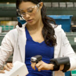 A warehouse worker using a wearable device with AI-embedded technology to scan an inventory item.