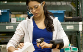 A warehouse worker using a wearable device with AI-embedded technology to scan an inventory item.